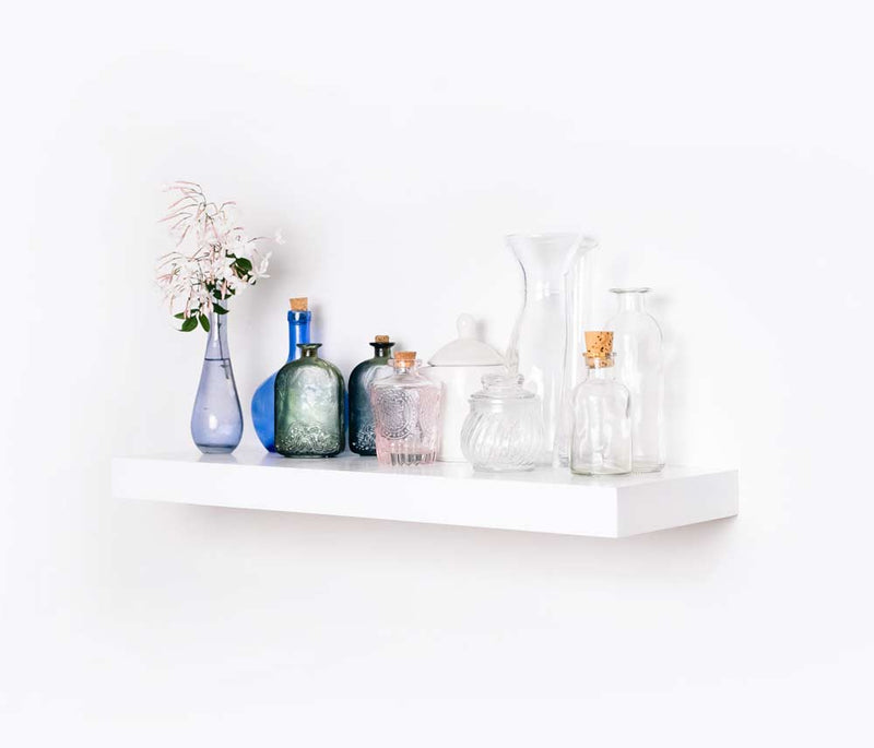A standard white econo floating shelf with homeware on top