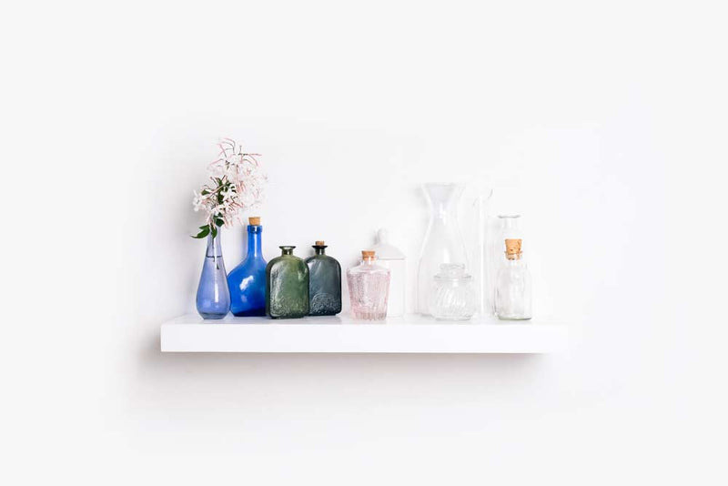 A standard white econo floating shelf with homeware on top